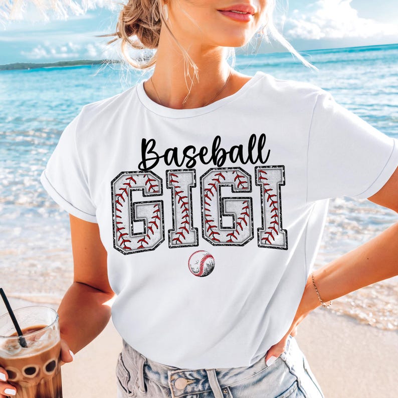 May include: White t-shirt with black text that reads "Baseball Gigi" with a baseball graphic design. The letters are outlined in red and white.