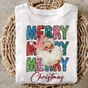 Op de afbeelding: Wit T-shirt met een kleurrijk glitterend "Merry Christmas" ontwerp met een vintage illustratie van de kerstman.