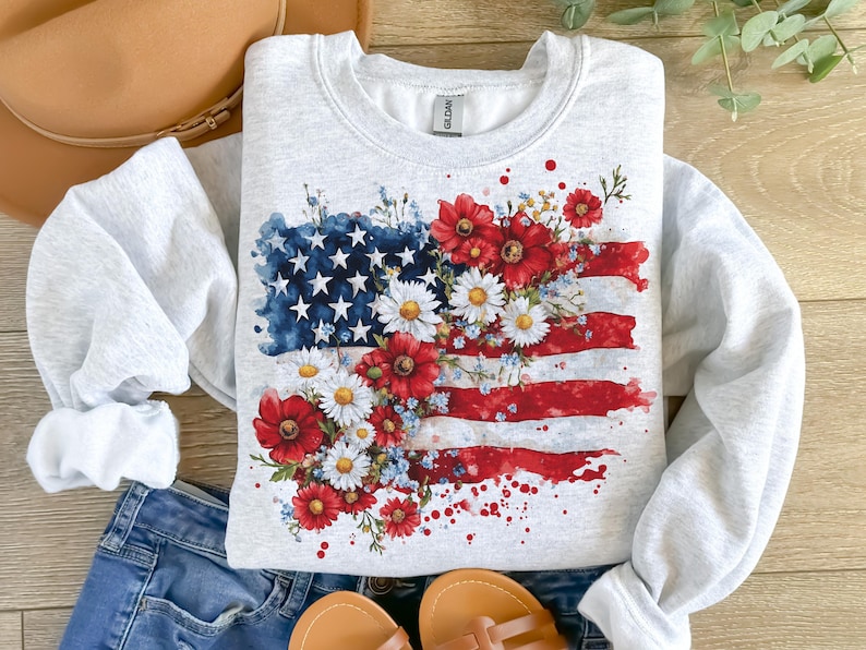 May include: A gray sweatshirt with a watercolor design of an American flag with red, white, and blue flowers.