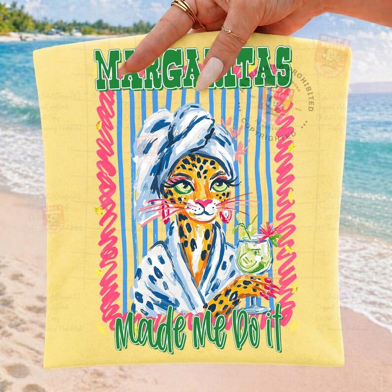 Pu&ograve; includere: Un telo mare giallo con un leopardo dei cartoni animati con un asciugamano e un accappatoio, che tiene in mano un cocktail. L'asciugamano ha le parole "Margaritas" e "Made Me Do It" in verde, con strisce blu e accenti rosa.