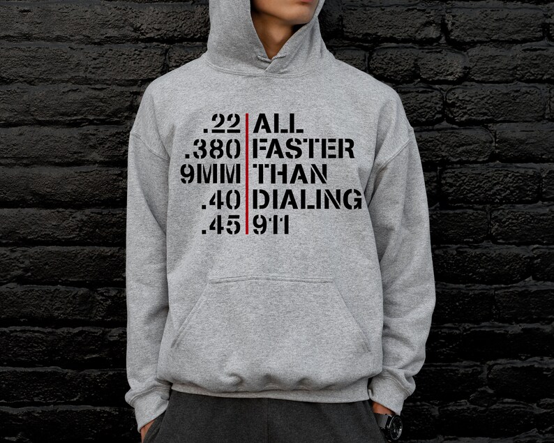May include: A gray hooded sweatshirt with a black graphic print that reads ".22 ALL FASTER THAN DIALING 911". The text is separated by a red vertical line.