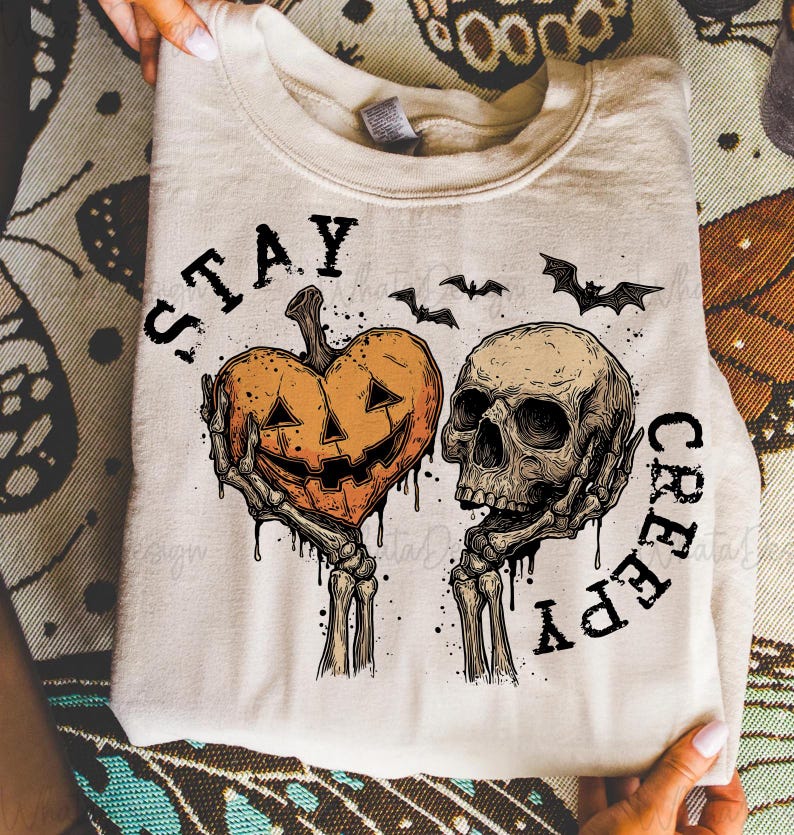 Puede incluir: Sudadera beige con dise&ntilde;o de Halloween. El gr&aacute;fico incluye un coraz&oacute;n de calabaza y una calavera sostenidos por manos esquel&eacute;ticas, con las palabras "STAY CREEPY" y siluetas de murci&eacute;lagos. El dise&ntilde;o es en negro y naranja.