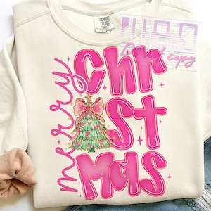 May include: Cream-colored sweatshirt with the words "Merry Christmas" in pink bubble letters. A Christmas tree with a pink bow and gold accents is in the center of the design. The sweatshirt is made of a soft material.