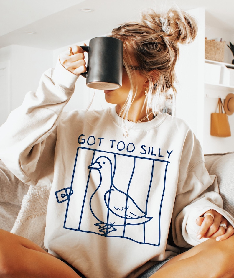 May include: A white sweatshirt with a blue graphic of a duck in a cage and the text "GOT TOO SILLY".