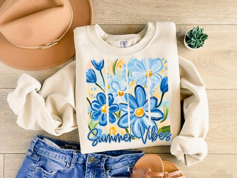May include: A cream-colored sweatshirt with a graphic of blue and yellow flowers and the text "Summer Vibes".