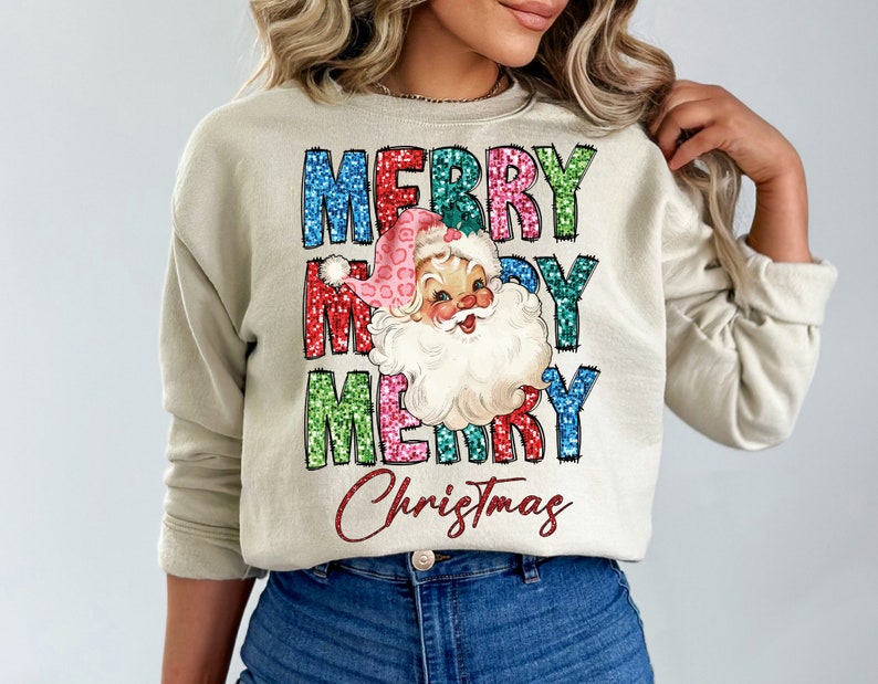 Op de afbeelding: Een beige sweatshirt met een feestelijk ontwerp met de woorden "Merry Christmas" in kleurrijke glitterletters en een vintage illustratie van de kerstman met een roze muts.