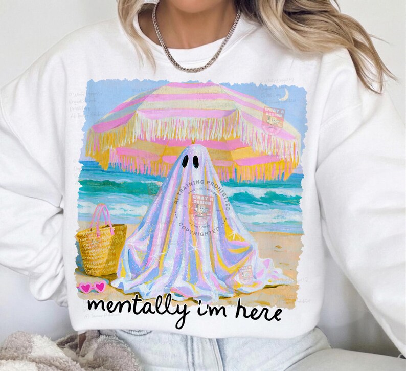 May include: A white crewneck sweatshirt featuring a graphic of a ghost under a pink and yellow striped beach umbrella on a sandy beach with a straw tote bag and pink heart-shaped sunglasses, with the text "mentally i'm here" printed below.