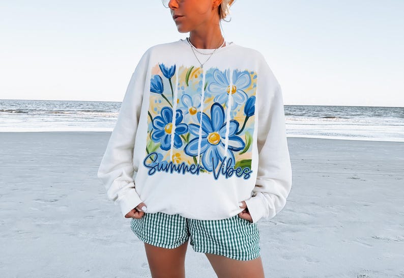 May include: White sweatshirt with a blue and yellow floral design and the text "Summer Vibes".