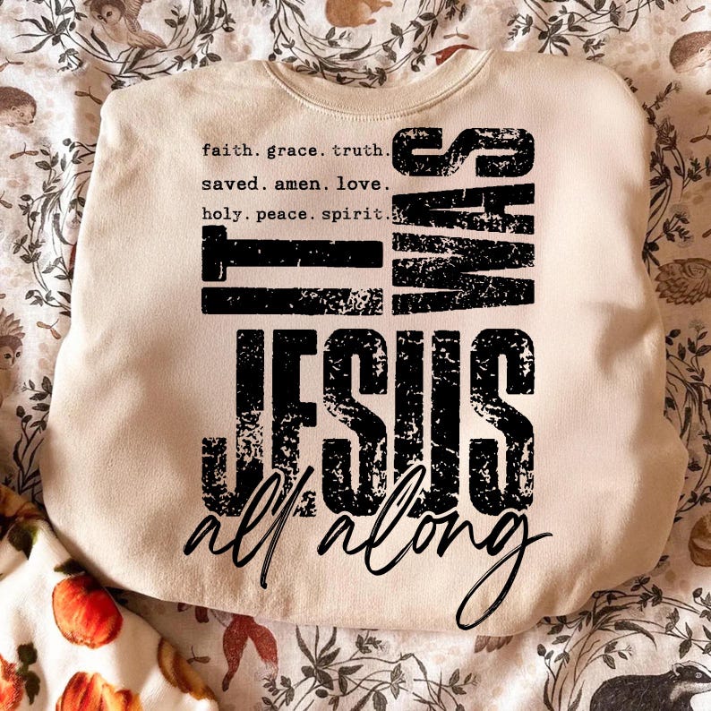 May include: Cream-colored sweatshirt with the text "IT WAS JESUS all along" in a distressed black font. The top includes a list of words like "faith, grace, truth" and "saved, amen, love". The sweatshirt is a casual, comfortable style.