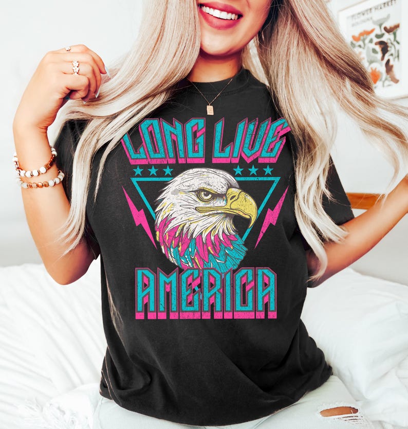 May include: Black t-shirt with a graphic of a bald eagle with pink, blue, and white accents. The text "Long Live America" is printed in pink, blue, and white letters.