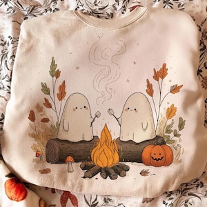 Digital Camping Ghosts Halloween PNG design featuring two ghosts around a campfire with a pumpkin and autumn leaves.