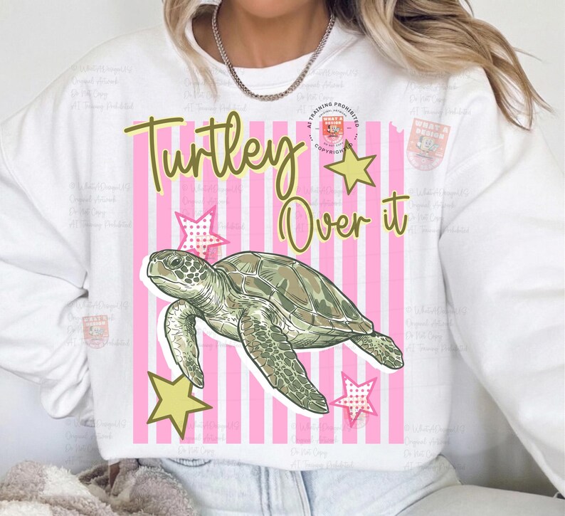 May include: White sweatshirt with a graphic design featuring a green sea turtle, yellow stars, and the text "Turley Over it" on a pink striped background. The design is centered on the front of the sweatshirt.