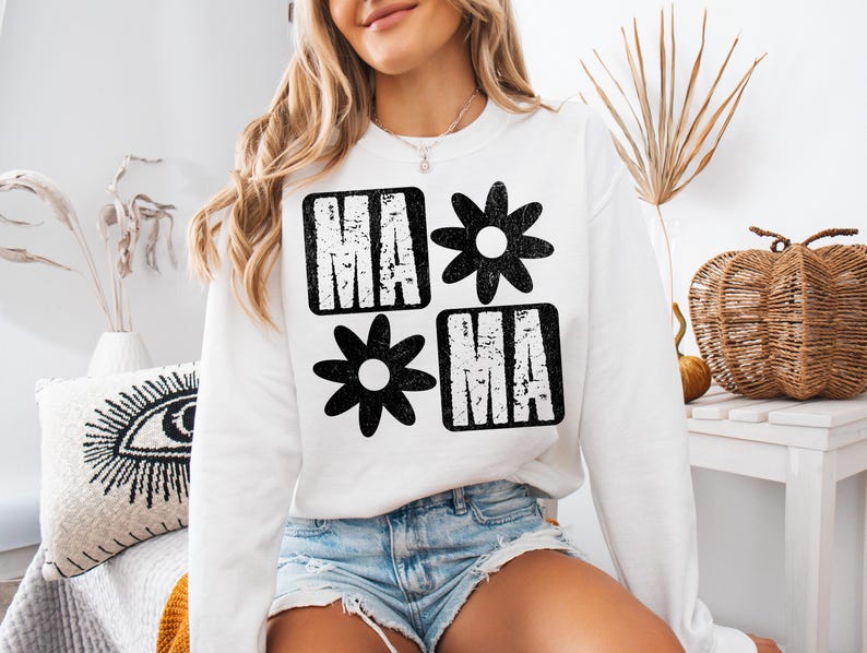Peut inclure: Sweat-shirt blanc avec un imprim&eacute; graphique noir du mot "MAMA" avec des fleurs stylis&eacute;es de chaque c&ocirc;t&eacute;.