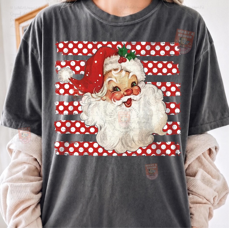 May include: A charcoal gray short-sleeve t-shirt featuring a graphic of a vintage-style Santa Claus wearing a red hat with a white pom-pom. The design includes horizontal red stripes with white polka dots behind the Santa illustration.
