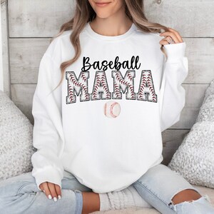 May include: White sweatshirt with the text "Baseball Mama" in black letters with red stitching around the letters. A baseball is below the text.