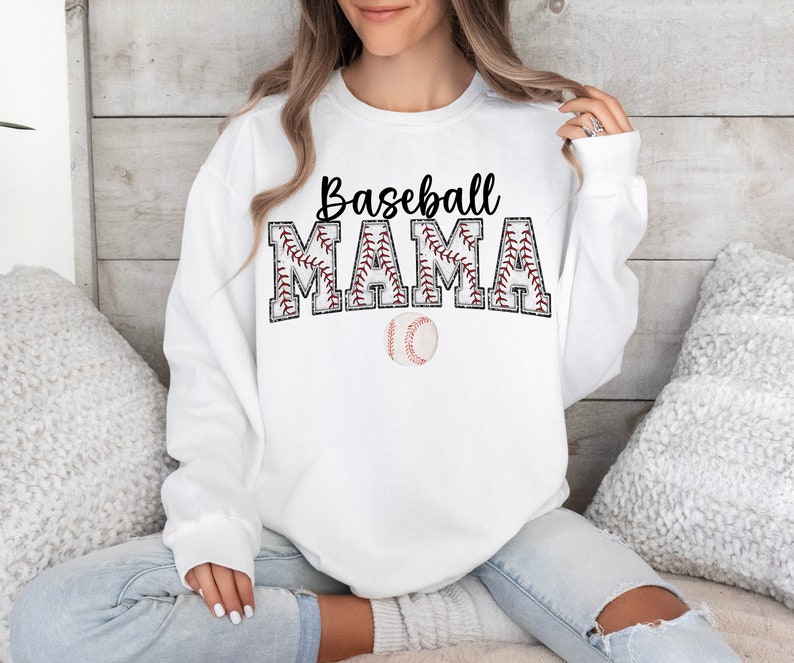 May include: White sweatshirt with the text "Baseball Mama" in black letters with red stitching around the letters. A baseball is below the text.