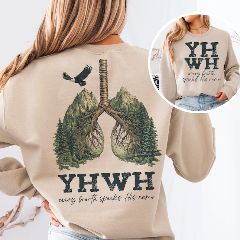 May include: Tan sweatshirt with a graphic of a pair of lungs made of trees and an eagle flying above. The text "YHWH every breath speaks His name" is printed below the graphic.