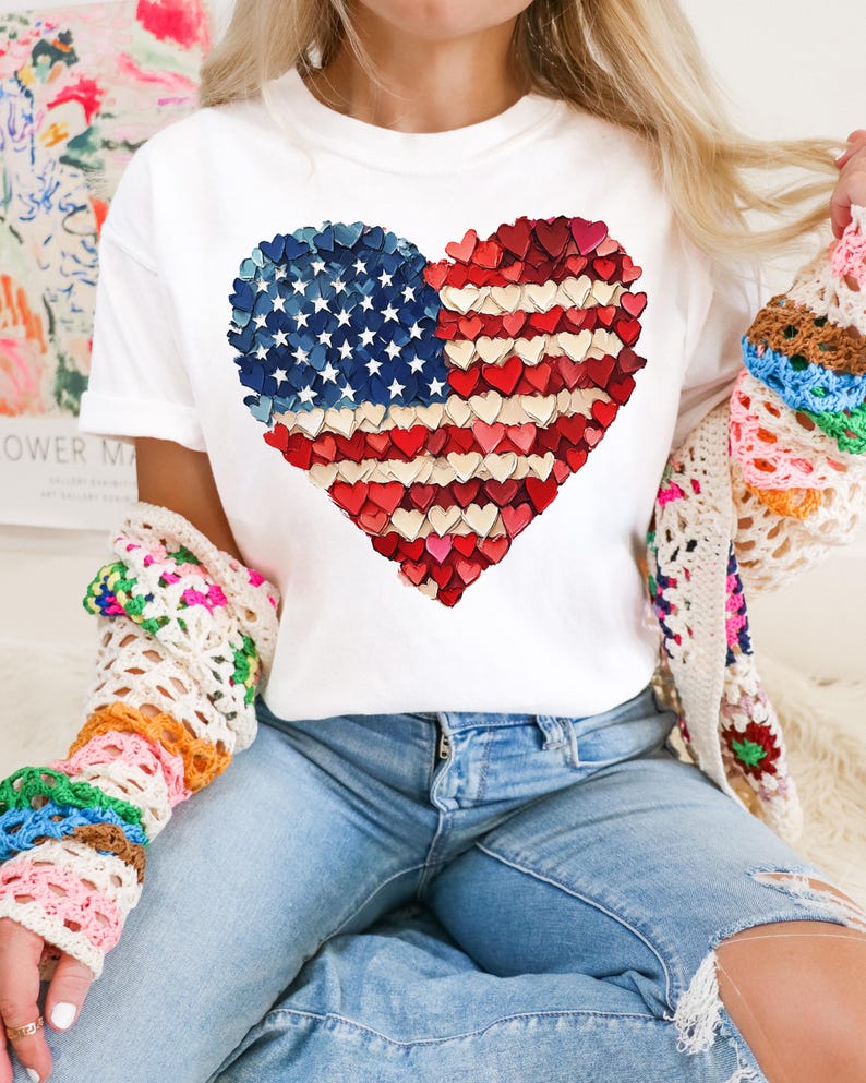 May include: White t-shirt with a red, white, and blue heart-shaped American flag design made of small hearts.