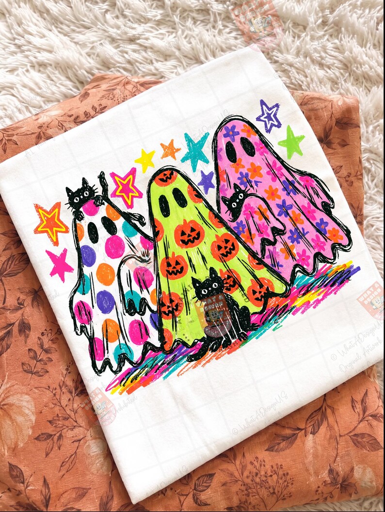 K&ouml;nnte beinhalten: Ein wei&szlig;es T-Shirt mit einer bunten Grafik von drei Geistern und drei schwarzen Katzen. Die Geister sind mit Punkten, K&uuml;rbissen und Blumen verziert. Das Design enth&auml;lt leuchtende Sterne in Gelb, Orange, Blau und Lila sowie eine regenbogenfarbene Basis.