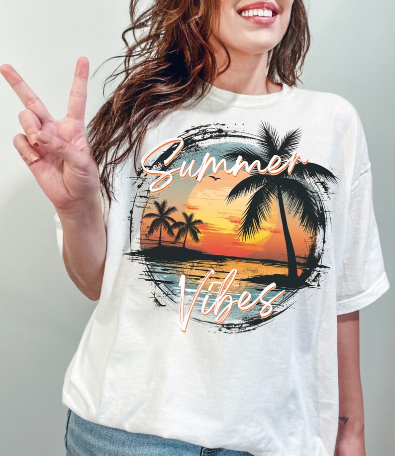 May include: White t-shirt with a graphic print of a sunset over the ocean with palm trees and the text "Summer Vibes".