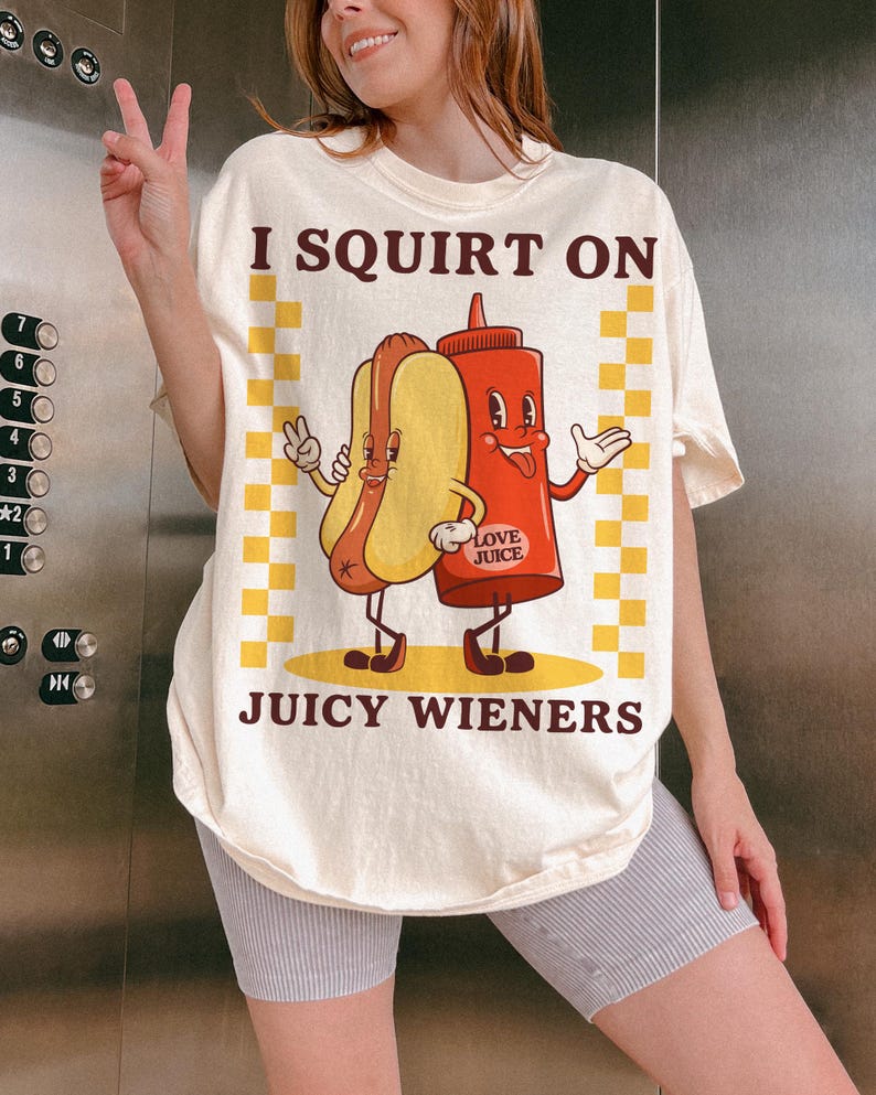 May include: A white t-shirt with a graphic of a hot dog and a ketchup bottle with the text "I SQUIRT ON JUICY WIENERS" and "LOVE JUICE" on the bottle.