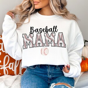 Peut inclure: Sweat-shirt blanc avec le texte "Baseball Mama" en noir avec des coutures rouges autour des lettres. Un ballon de baseball est centr&eacute; sous le texte.