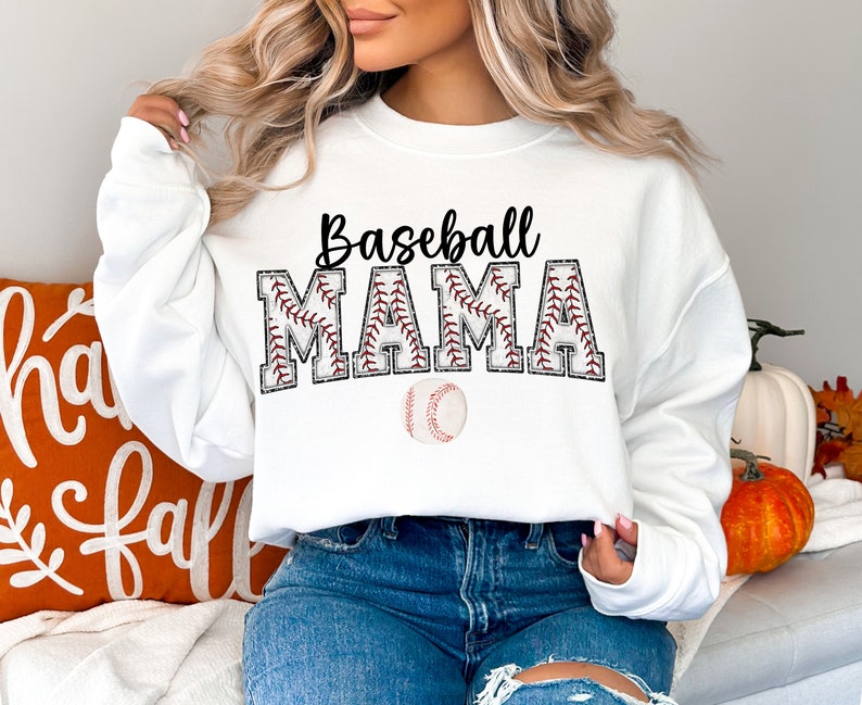 Peut inclure: Sweat-shirt blanc avec le texte "Baseball Mama" en noir avec des coutures rouges autour des lettres. Un ballon de baseball est centr&eacute; sous le texte.