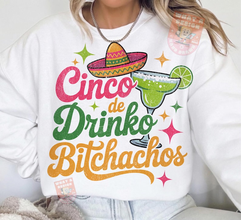 May include: White sweatshirt with a colorful graphic design. The design includes a sombrero, margarita, and the text "Cinco de Drinko Bitchachos" in pink, green, and orange. The design is accented with star shapes.
