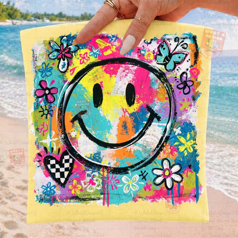 May include: A yellow square-shaped item with a large, black smiley face at the center. The face is surrounded by colorful abstract paint strokes in pink, blue, yellow, and green. Floral and butterfly designs are also present.