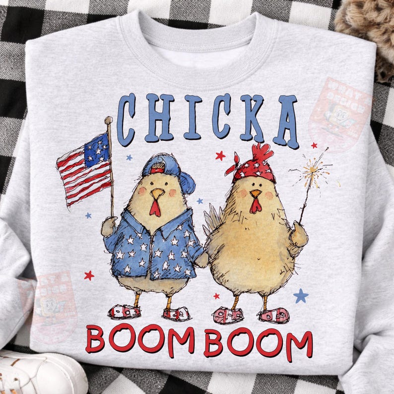 May include: A light gray sweatshirt featuring two cartoon chickens celebrating with an American flag and a sparkler. The text "CHICKA BOOM BOOM" is printed in blue and red. The chickens are wearing patriotic clothing.