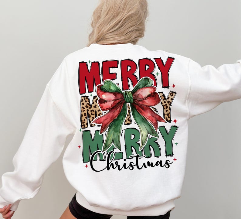 K&ouml;nnte beinhalten: Wei&szlig;er Pullover mit einem roten, gr&uuml;nen und schwarzen Grafikdruck, auf dem "Merry Merry Christmas" mit einer gro&szlig;en gr&uuml;nen und roten Schleife steht.