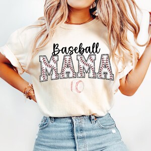 May include: A white t-shirt with the text "Baseball Mama" in black letters with a red baseball stitch design. A baseball is below the text.
