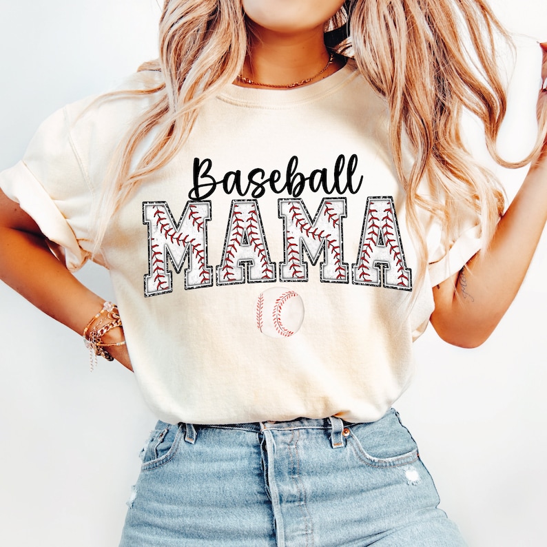 May include: A white t-shirt with the text "Baseball Mama" in black letters with a red baseball stitch design. A baseball is below the text.