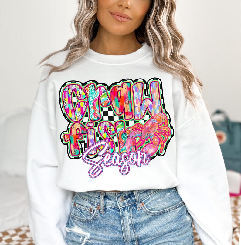 May include: White sweatshirt with a colorful graphic design that says "Crawfish Season" with a pink crawfish illustration.