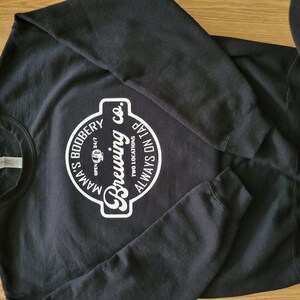 May include: Black sweatshirt with a white logo that says "Mama's Boobery Brewing Co. Two Locations Always On Tap" in a circle.