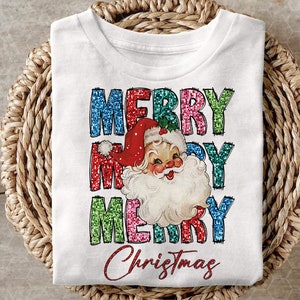 Op de afbeelding: Wit T-shirt met een kleurrijk glitterend "Merry Christmas" ontwerp met een vintage illustratie van de kerstman.