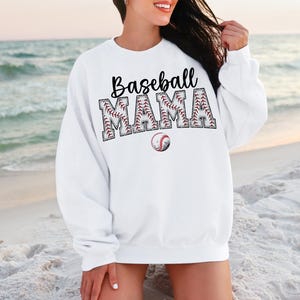 May include: White sweatshirt with the text "Baseball Mama" in black letters with a baseball graphic design. The letters are outlined in red and white stitching.