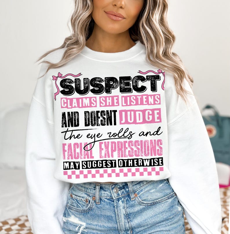 May include: White sweatshirt with pink and black text that reads "SUSPECT CLAIMS SHE LISTENS AND DOESNT JUDGE the eye rolls and FACIAL EXPRESSIONS MAY SUGGEST OTHERWISE".