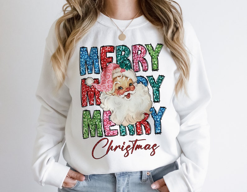 Op de afbeelding: Witte trui met een feestelijk ontwerp met een vintage illustratie van de kerstman en de tekst "Merry Merry Christmas" in kleurrijke glinsterende letters.