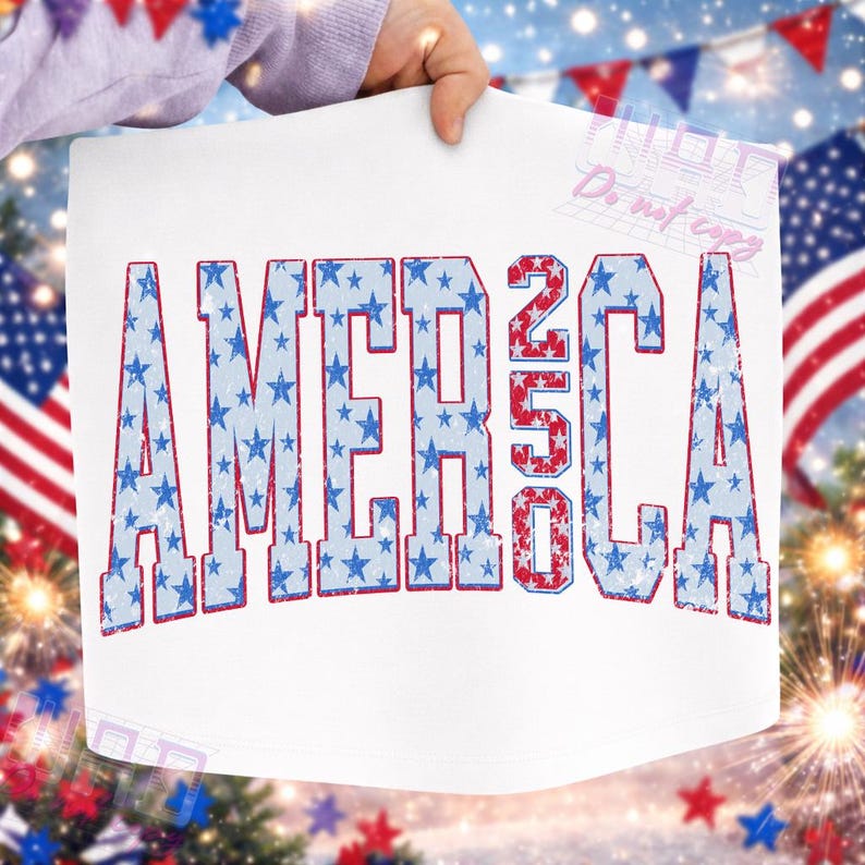 May include: White rectangular print with the word "AMERICA" in large, distressed, blue letters filled with blue stars. The number "250" is in red. The print is held up by a person.