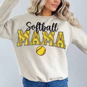 May include: A beige sweatshirt with the text "Softball Mama" in black and yellow with a softball graphic.