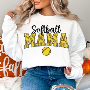 May include: White sweatshirt with the text "Softball Mama" in black with a yellow softball graphic. The sweatshirt has long sleeves and a crew neck.