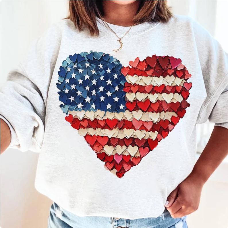 May include: A white sweatshirt with a red, white, and blue American flag design in the shape of a heart. The flag is made up of small hearts.