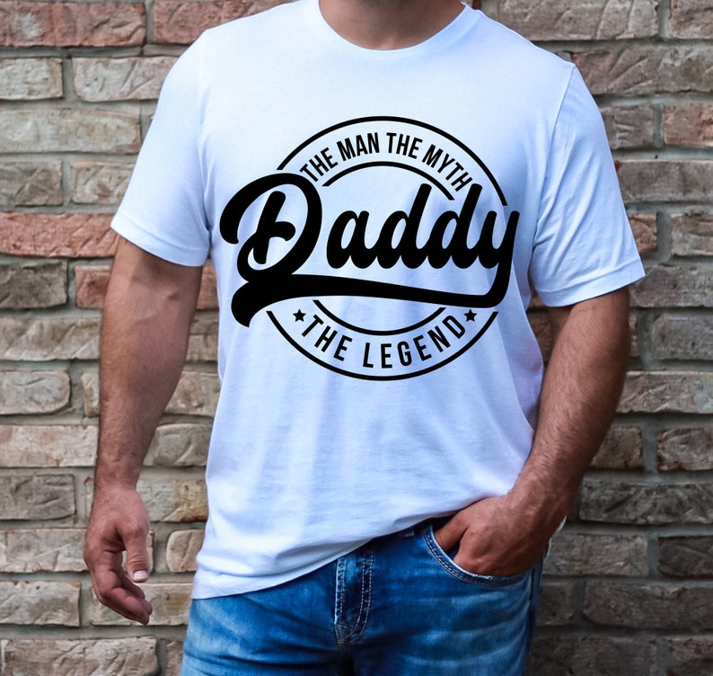 May include: White t-shirt with a black circle graphic that says "The Man The Myth Daddy The Legend".