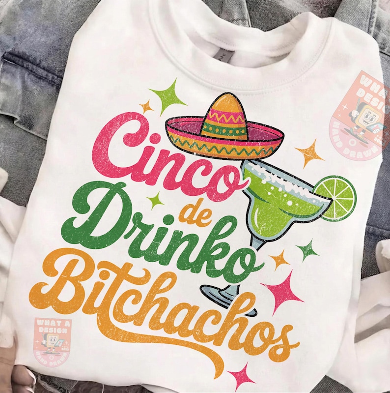 May include: White sweatshirt with a colorful graphic design. The design features the words "Cinco de Drinko Bitchachos" in pink, green, and orange, along with a sombrero and a margarita glass. The design is festive and fun.