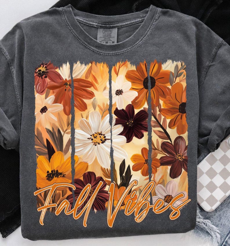 May include: Dark gray sweatshirt featuring a floral design in shades of orange, white, and burgundy. The words "Fall Vibes" are printed in orange script across the bottom of the floral design. The sweatshirt has long sleeves and a crew neck.