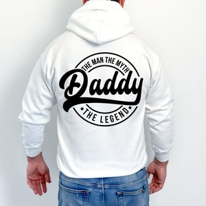 May include: White hooded sweatshirt with a black circular design on the back that says "The Man The Myth Daddy The Legend".