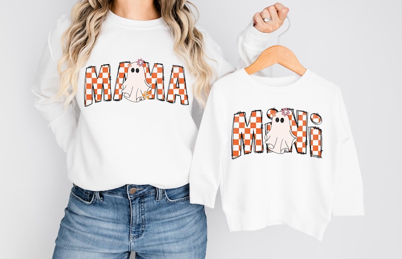 Pu&ograve; includere: Camicie bianche a maniche lunghe con fantasie di fantasmi a scacchi arancioni e bianchi. La camicia pi&ugrave; grande dice "MAMA" e quella pi&ugrave; piccola dice "MINI".