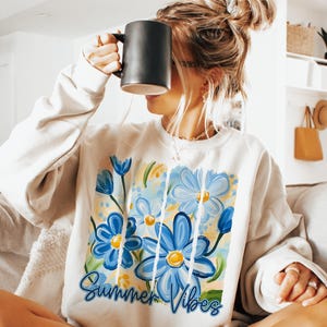 May include: A white sweatshirt with a blue and yellow floral design and the text "Summer Vibes".