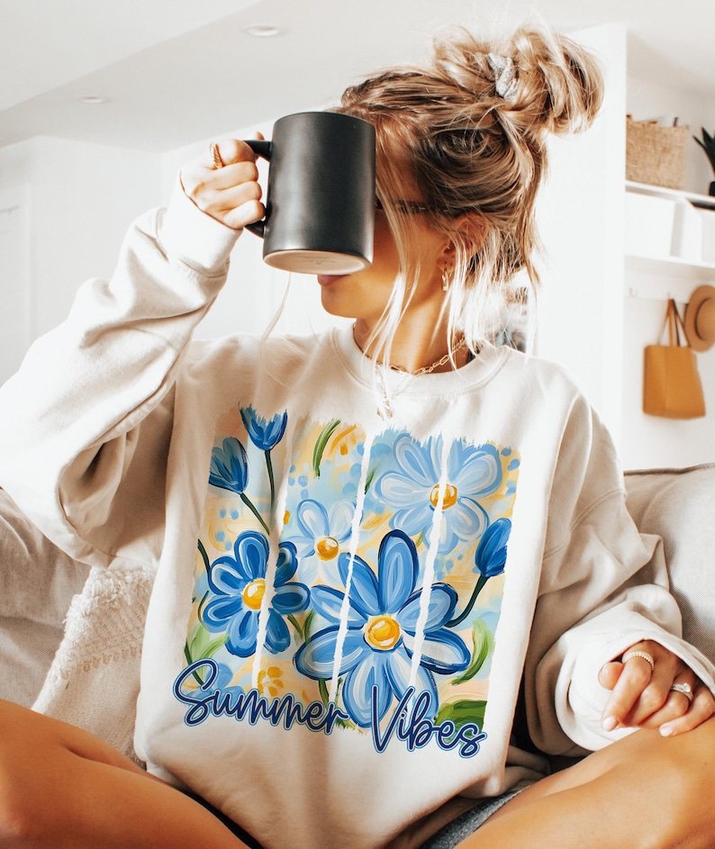 May include: A white sweatshirt with a blue and yellow floral design and the text "Summer Vibes".
